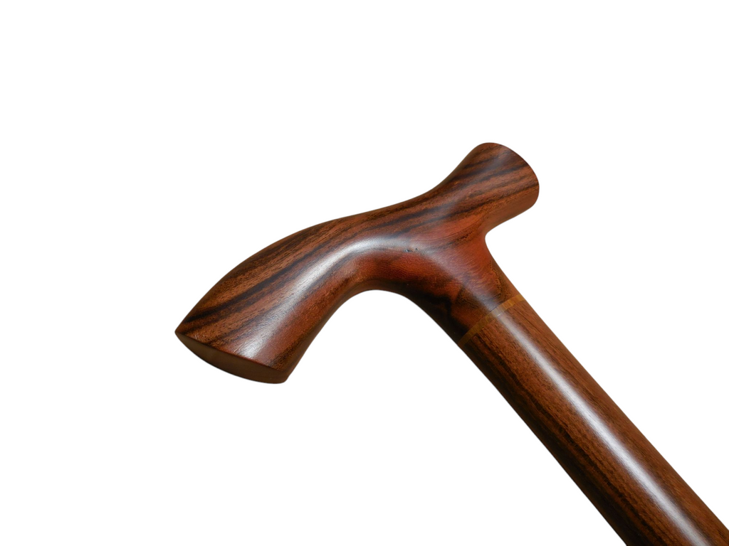 Tikal walking cane handle angled to the left, showing the sweep of the T-top into the laurel wood shaft