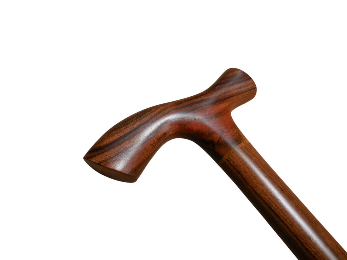 Tikal walking cane handle angled to the left, showing the sweep of the T-top into the laurel wood shaft